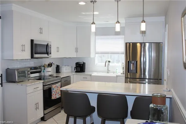 a kitchen with stainless steel appliances granite countertop a stove a refrigerator a sink dishwasher a stove with chairs and white cabinets