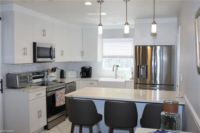 a kitchen with stainless steel appliances granite countertop a stove a refrigerator a sink dishwasher a stove with chairs and white cabinets