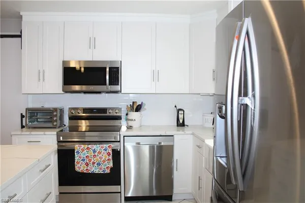 a kitchen with stainless steel appliances a refrigerator stove and white cabinets