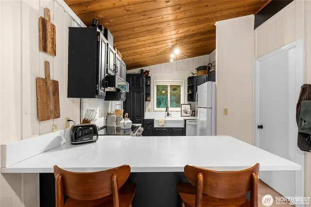 a kitchen with stainless steel appliances granite countertop a dining table chairs and a refrigerator