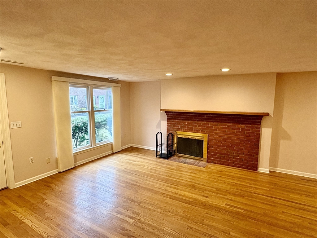 224 Park Street, Unit B2 Stoneham, MA 02180 - Photo 5 of 35 an empty room with wooden floor fireplace and windows