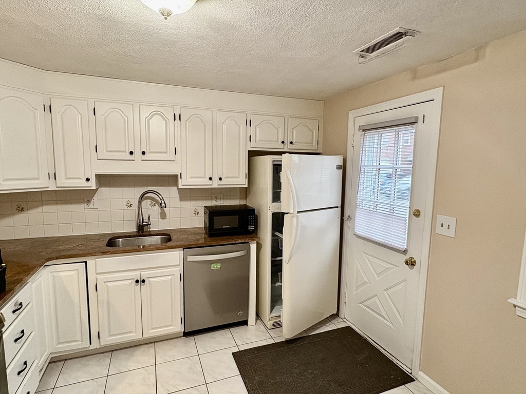 224 Park Street, Unit B2 Stoneham, MA 02180 - Photo 9 of 35 a kitchen with white cabinets and refrigerator