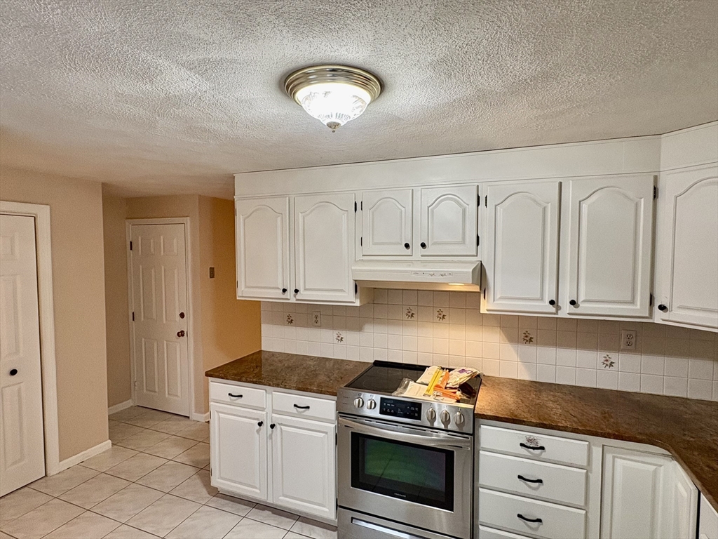 224 Park Street, Unit B2 Stoneham, MA 02180 - Photo 10 of 35 a kitchen with granite countertop white cabinets and stainless steel appliances