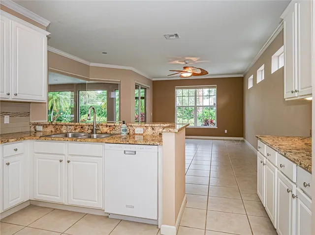 a open kitchen with granite countertop a stove a sink dishwasher and white cabinets with wooden floor