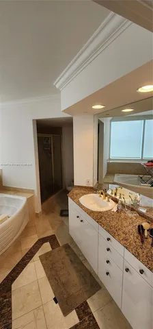 a spacious bathroom with a granite countertop sink a mirror and a bathtub