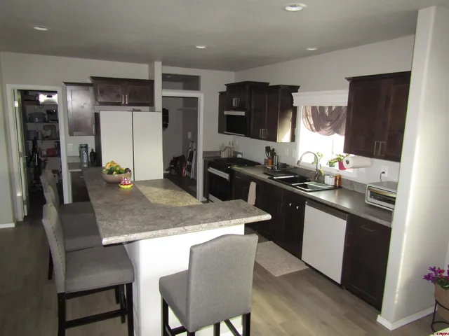a kitchen with stainless steel appliances granite countertop a sink a stove a refrigerator a dining table and chairs