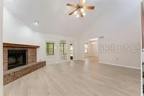 a view of an empty room with chandelier fan and fire place