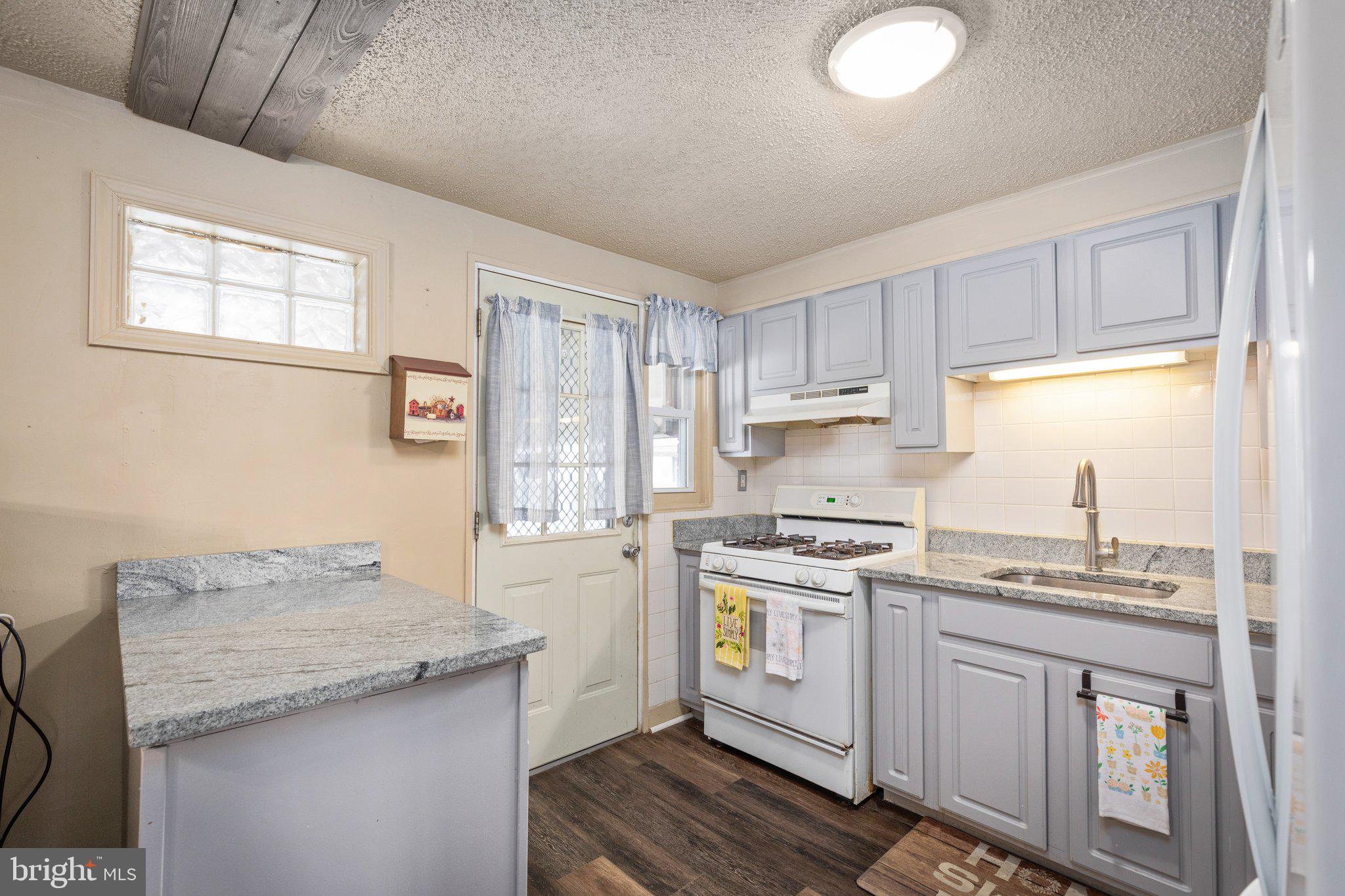 7404 Edsworth Road Dundalk, MD 21222 - Photo 8 of 24 a kitchen with granite countertop a sink stove and cabinets