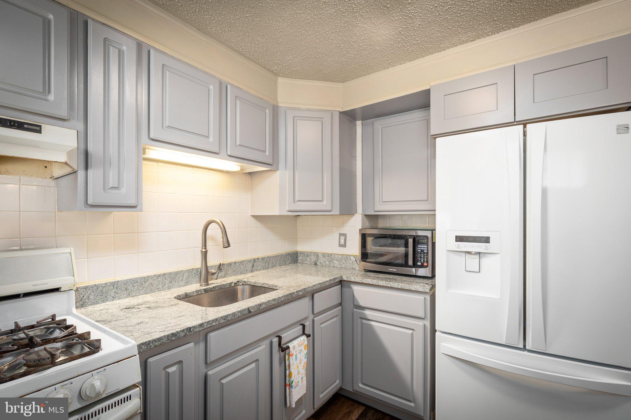 7404 Edsworth Road Dundalk, MD 21222 - Photo 9 of 24 a kitchen with white cabinets and white appliances