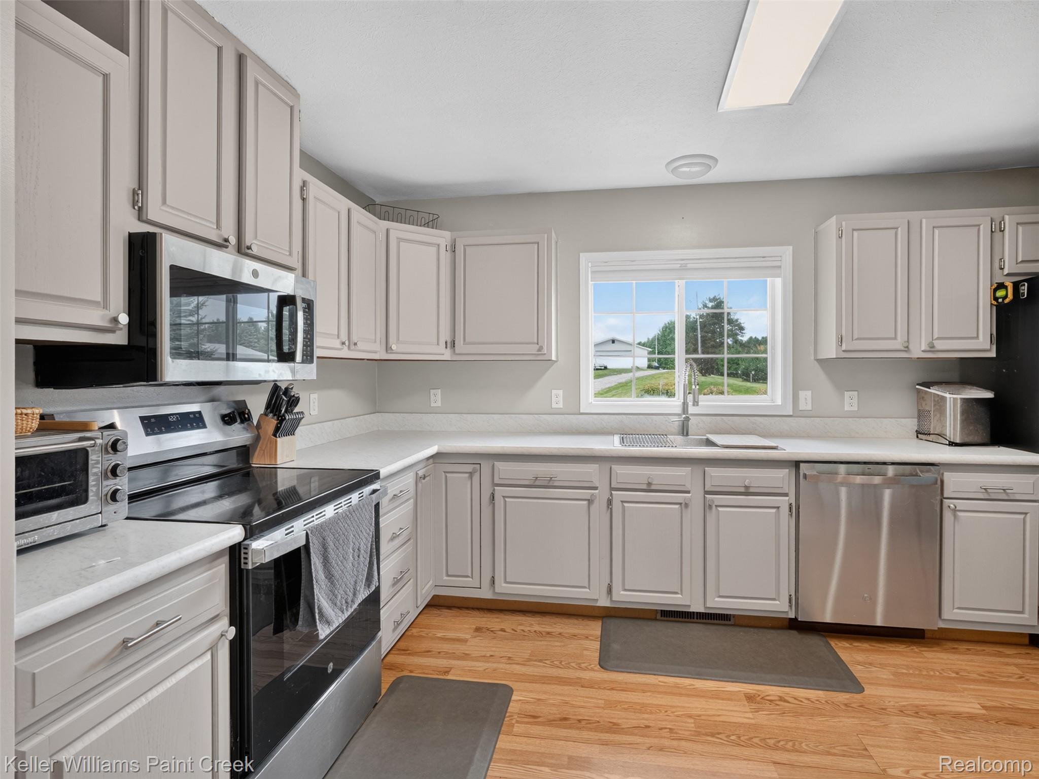 533 White Road Gladwin, MI 48624 - Photo 5 of 69 Peninsula counter with a breakfast bar, wood-finish flooring, and white kitchen cabinetry