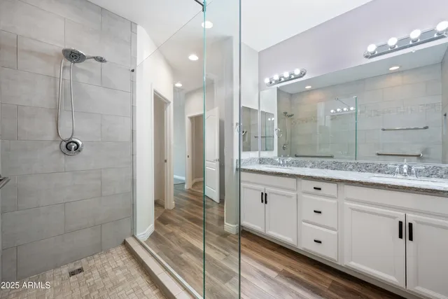 a spacious bathroom with a granite countertop sink a mirror and a shower