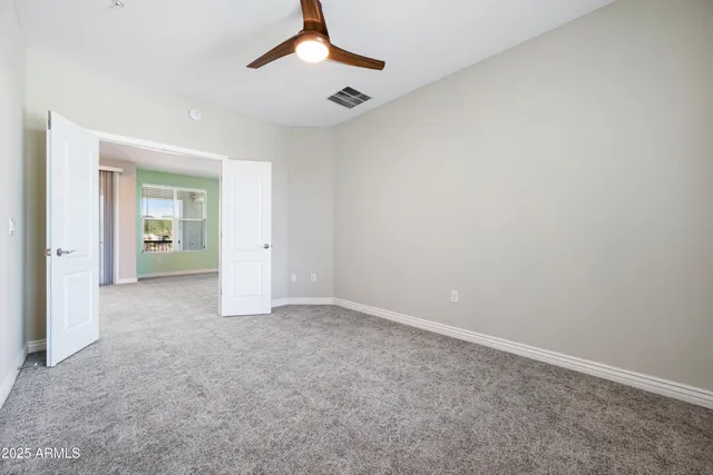 an empty room with windows and a ceiling fan