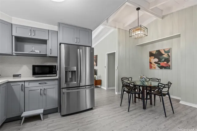 a kitchen with stainless steel appliances a refrigerator a stove a dining table and chairs with wooden floor