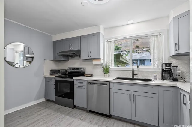 a kitchen with stainless steel appliances granite countertop a stove a sink dishwasher and white cabinets with wooden floor