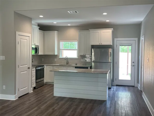 a view of a room with wooden floor a ceiling fan and windows
