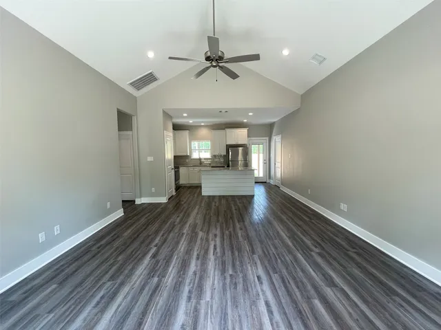 a large kitchen with stainless steel appliances granite countertop a refrigerator a sink dishwasher a stove and a microwave oven on wooden floor