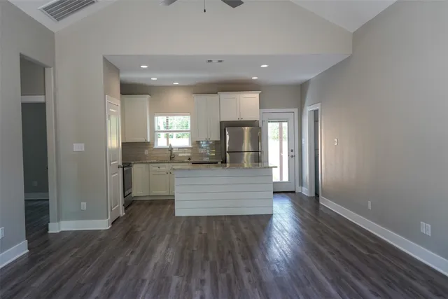a kitchen with kitchen island a sink wooden floor and refrigerator