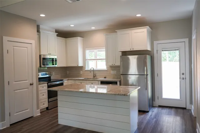 an empty room with wooden floor windows and fan