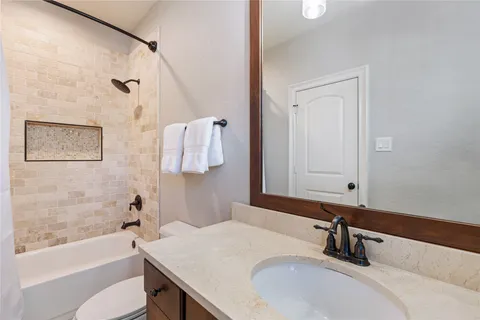 a bathroom with a sink vanity granite tub and a mirror