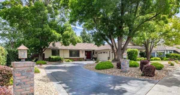 a front view of a house with garden and trees
