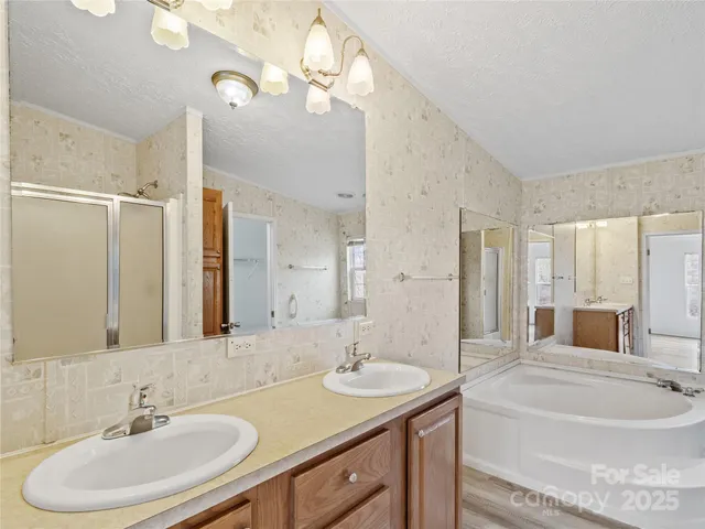 a bathroom with a sink double vanity granite tub and a mirror