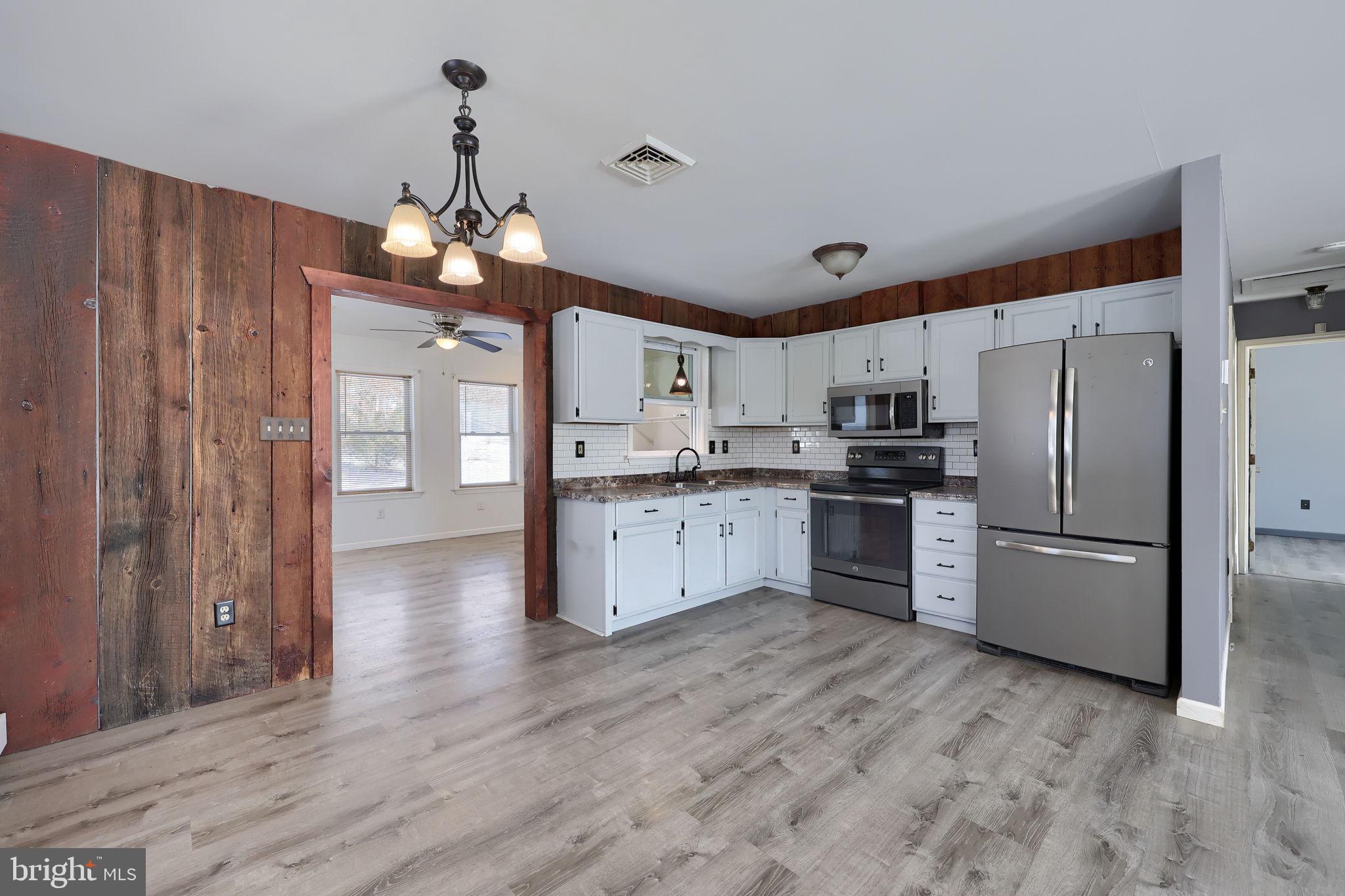 877 Richmond Road Windsor, PA 17366 - Photo 13 of 40 a kitchen with stainless steel appliances granite countertop a refrigerator a oven a sink dishwasher and white cabinets with wooden floor
