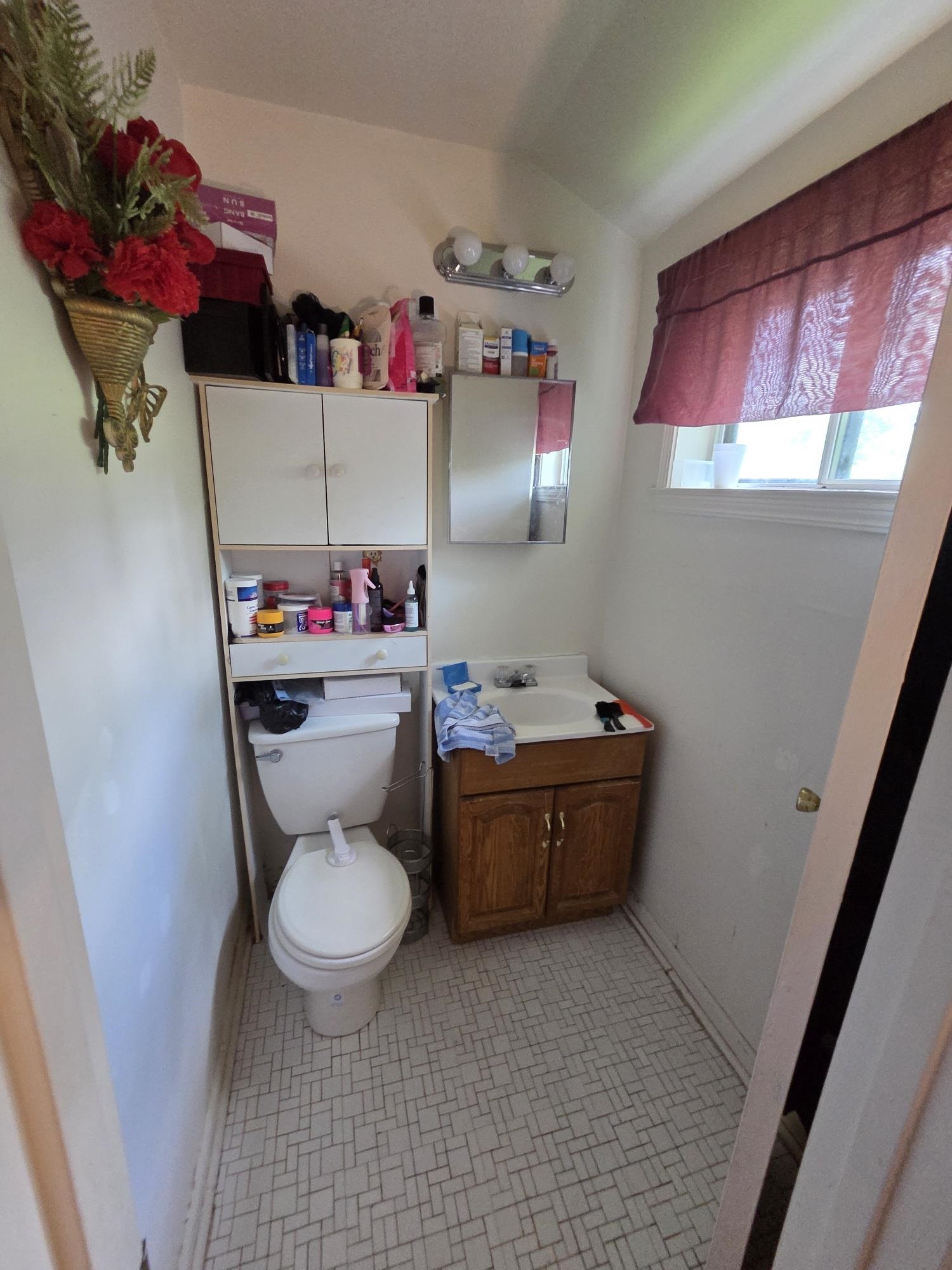 899 West Raines Road Memphis, TN 38109 - Photo 9 of 10 Compact bathroom featuring a white toilet, a wood-finish vanity with a built-in sink, and a mirrored medicine cabinet