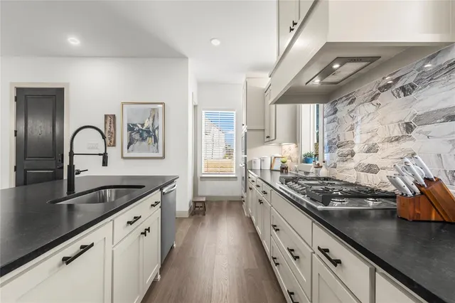 a kitchen with stainless steel appliances granite countertop a sink stove and cabinets