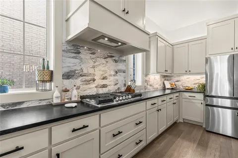 a kitchen with stainless steel appliances granite countertop a sink a refrigerator and white cabinets