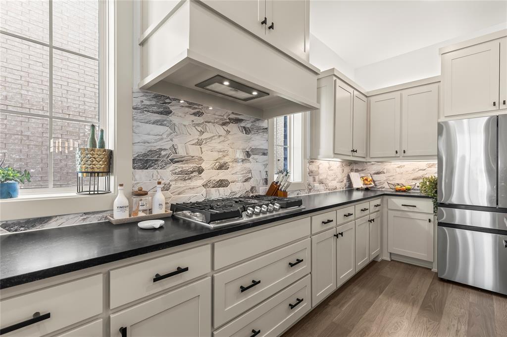 15627 Rue Drive Frisco, TX 75033 - Photo 8 of 35 a kitchen with stainless steel appliances granite countertop a sink a refrigerator and white cabinets