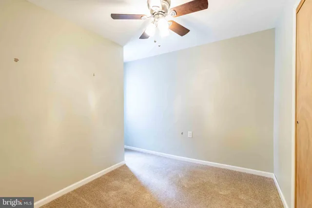 an empty room with a chandelier fan and closet