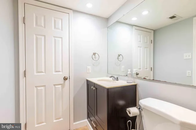a bathroom with a toilet sink vanity and mirror