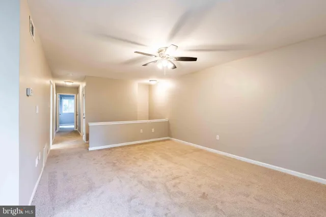 an empty room with chandelier fan and windows