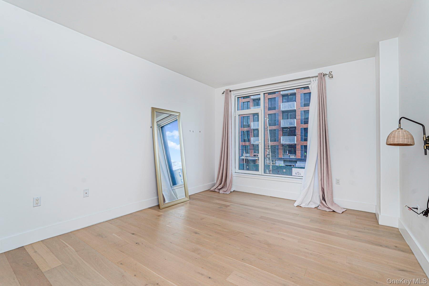 133 Beach 116th Street, Unit 2C Queens, NY 11694 - Photo 25 of 35 an empty room with wooden floor and windows