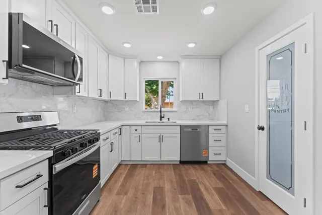 a kitchen with stainless steel appliances granite countertop a stove a sink and a microwave