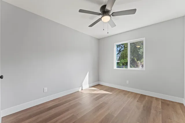 an empty room with a window and a fan