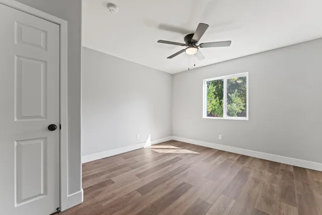 an empty room with wooden floor closet and windows