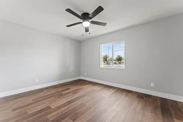 an empty room with wooden floor and ceiling fan