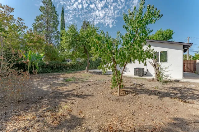 a view of a house with backyard and trees