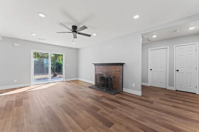 an empty room with wooden floor a fireplace and windows