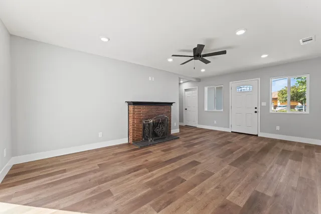 an empty room with chandelier fan and fireplace