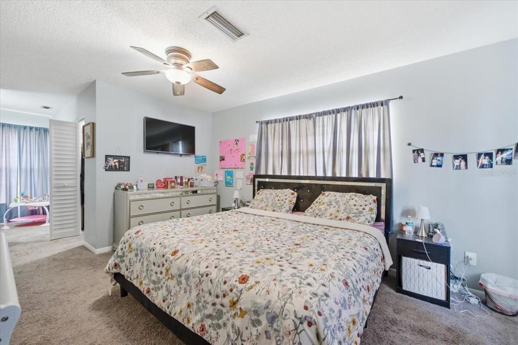 4464 Bromley Avenue Spring Hill, FL 34609 - Photo 28 of 43 a bedroom with a bed and a flat tv screen on dresser