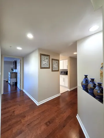 a view of empty room with wooden floor and kitchen