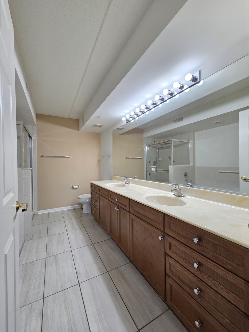 6815 North Milwaukee Avenue, Unit 210 Niles, IL 60714 - Photo 33 of 47 a bathroom with a double vanity sink and a mirror