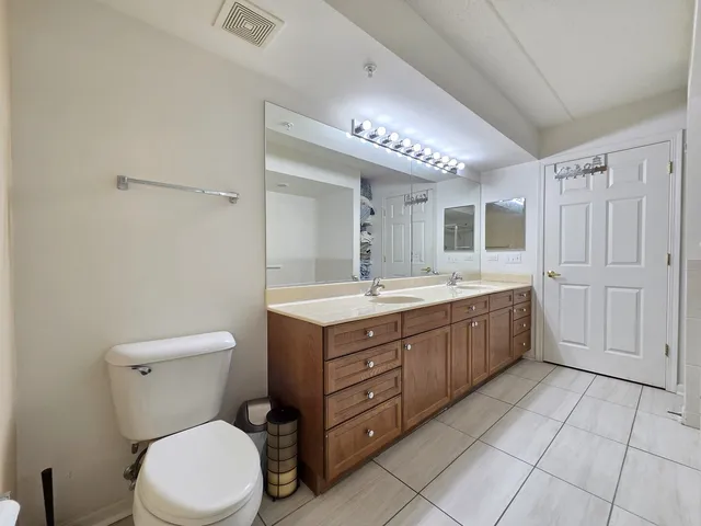 a bathroom with a double vanity sink a toilet mirror and vanity