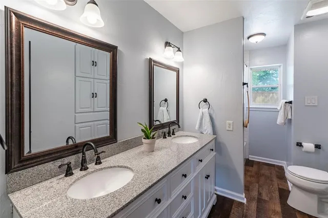 a bathroom with a granite countertop sink a toilet and a mirror
