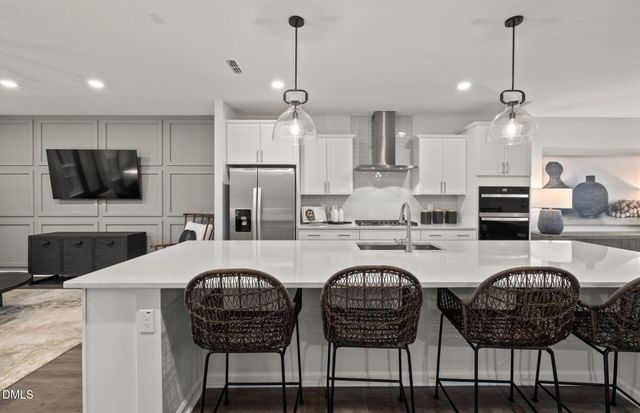 a kitchen with stainless steel appliances a dining table chairs stove and refrigerator