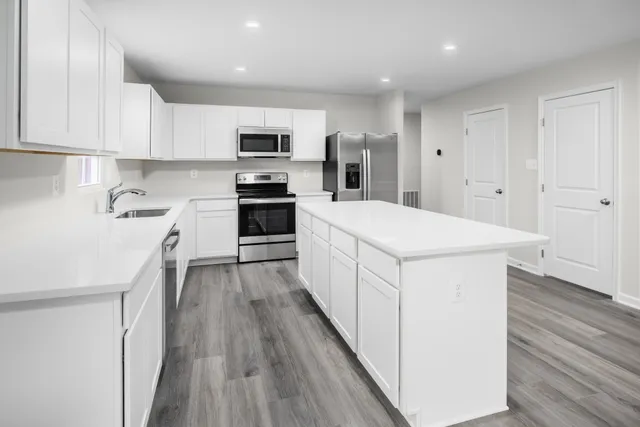 a kitchen with stainless steel appliances a white refrigerator cabinets and wooden floor