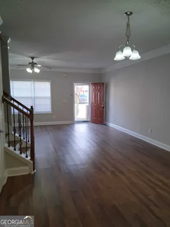 a view of a room with wooden floor chandelier and windows