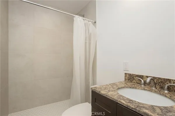 a bathroom with a granite countertop sink toilet and a mirror